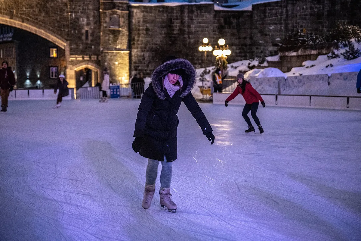 Skaters on an outdoor rink in a city square, historic buildings behind