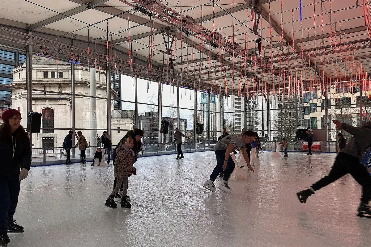 People ice skating on an outdoor rink in a city centre