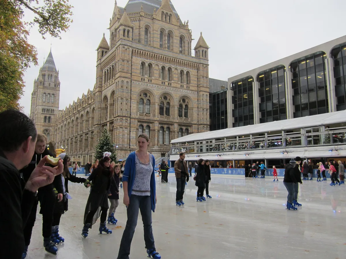 People ice skating outside a grand museum building, families on the ice