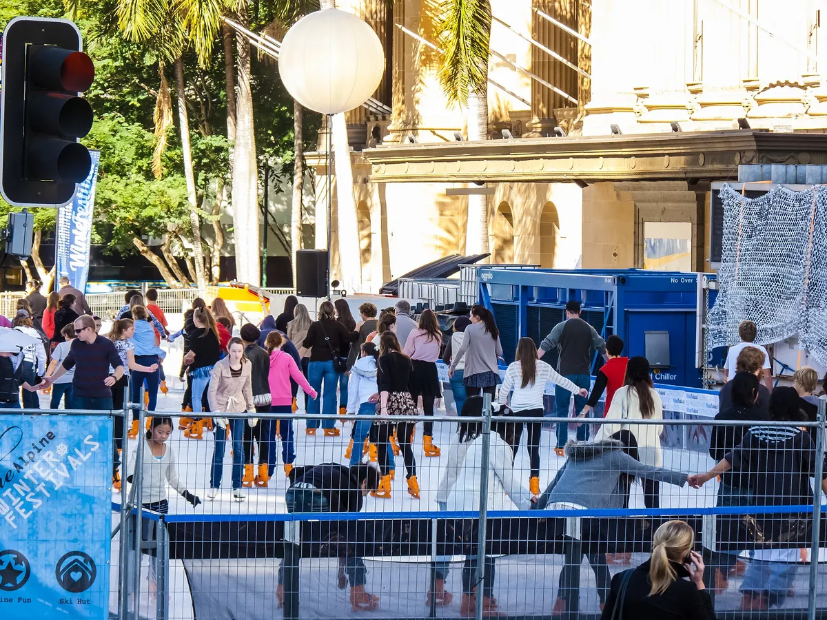 A crowded outdoor rink at a winter festival, skaters in bright rental skates