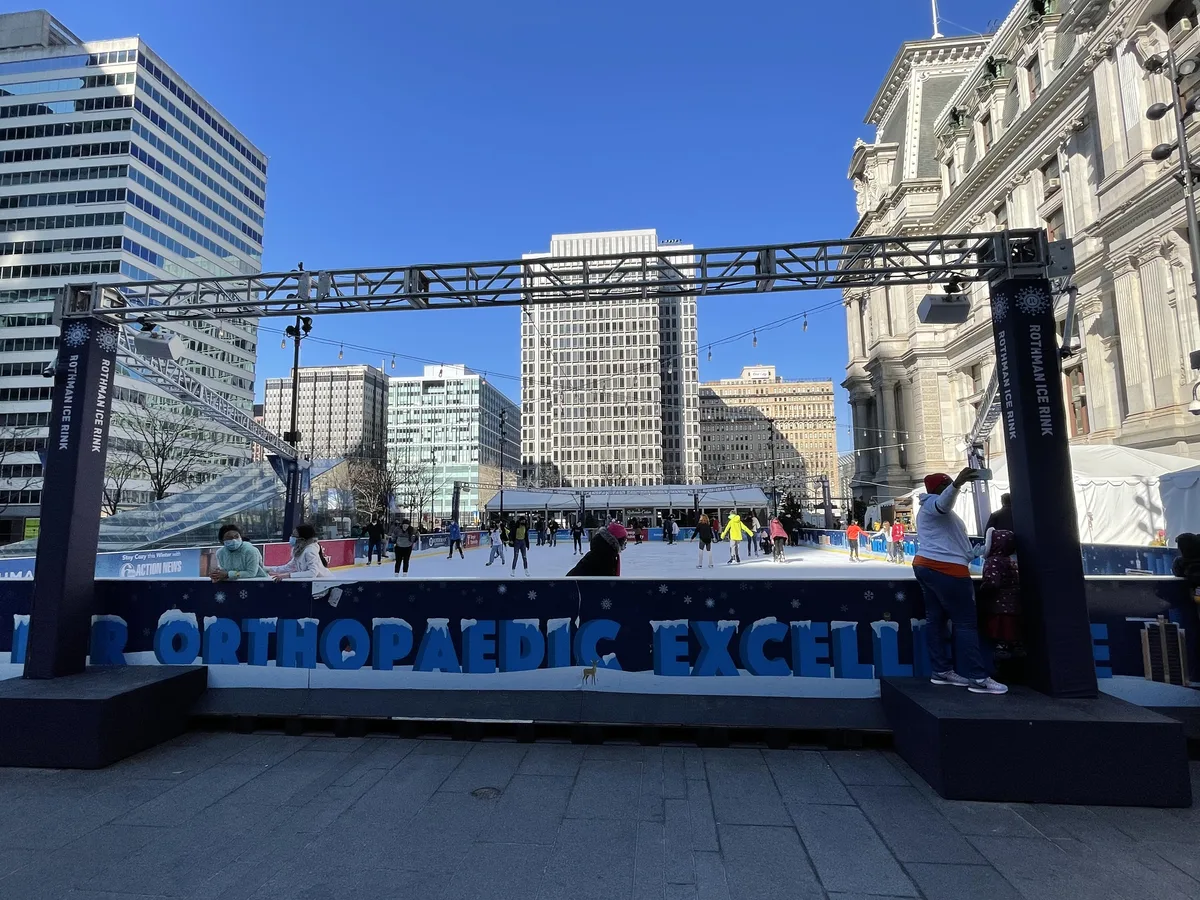 Skaters on the ice at the Rothman Ice Rink in Dilworth Park, Philadelphia, with City Hall beside the rink, February 2022